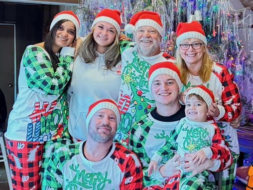 A family gathered together in matching holiday pajamas