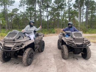 Two riders on all-terrain vehicles on a sandy trail