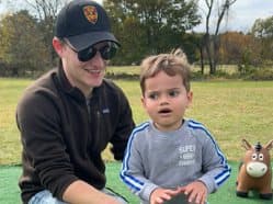 A man playing outdoors on the grass with a toddler