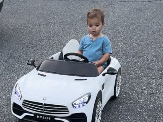 A toddler sitting in a toy ride-on car